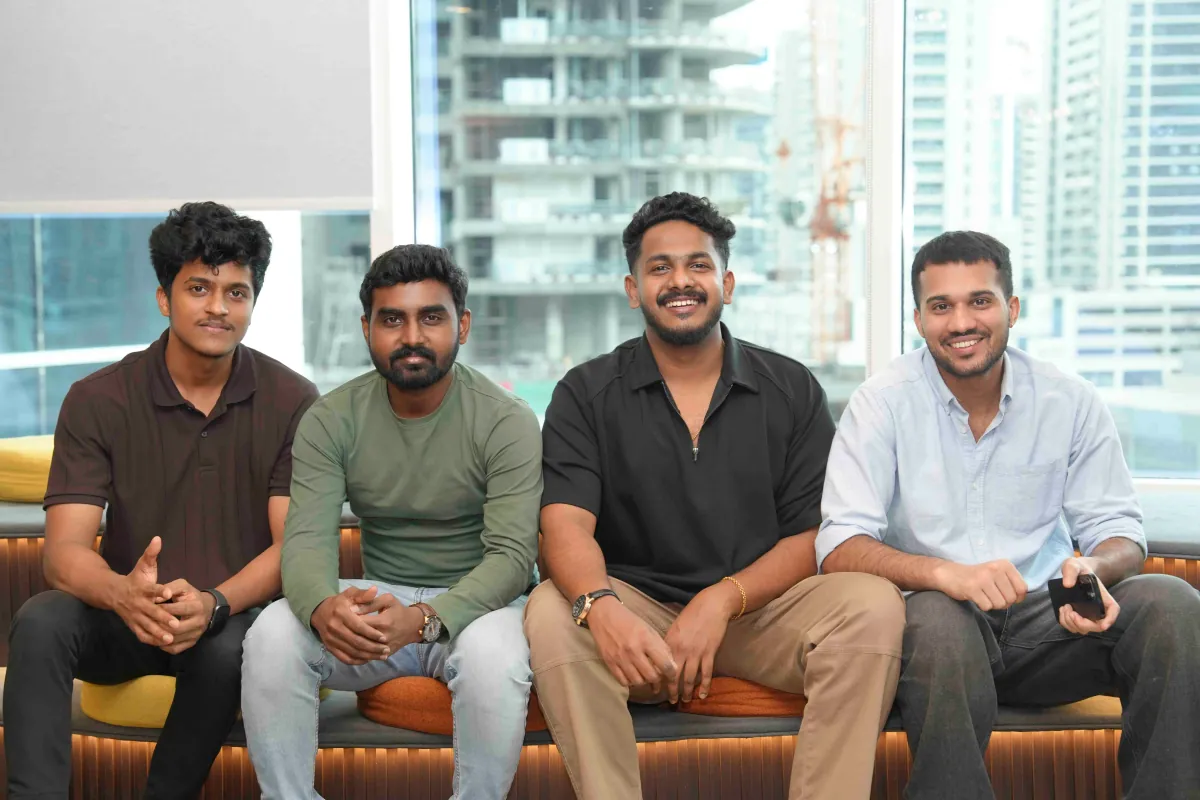 Four members of the 3X Studio team on the window bench, the Dubai skyline behind them