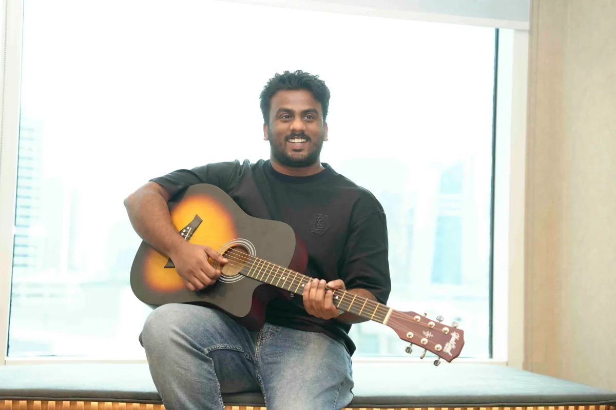 A 3X Studio team member playing an acoustic guitar by the office window